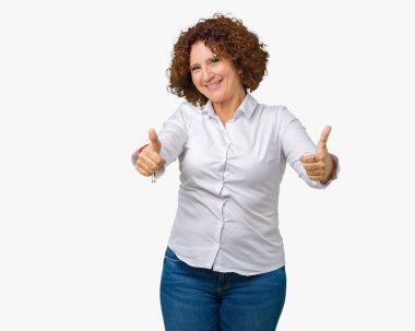 Güzel orta ager üst düzey businees kadın el ile pozitif jest yapıyor onaylama izole arka plan üzerinde başparmak gülümseyen ve başarı için mutlu. Kamera, kazanan jest arıyorsunuz.