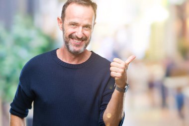 Orta yaş ağarmış komuta sizde seyir ve başparmak yanında yukarıyı mutlu yüz ile gülümseyen izole arka plan üzerinde.