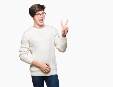 Mutlu yüz zafer işareti yaparken kameraya göz kırpıyor ile gülümseyen izole arka plan üzerinde gözlük takan yakışıklı delikanlı. İki numaralı.