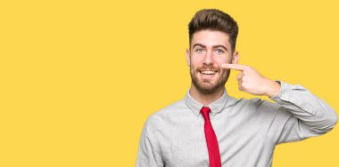 Genç yakışıklı iş yüz ve burun, neşeli gülümseyerek el parmak ile işaret dostum