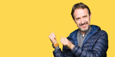 Orta yaş yakışıklı adam giyen kış ceket arkasından el ve kadar başparmak ile işaret emin gülümseyen