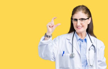 Orta yaş olgun doktor kadın izole arka plan gülümseyen ve boyutu işaret parmaklı ararken ve kamera işi el ile kendinden emin eller üzerinde tıbbi bir palto giyiyor. Ölçü kavramı.