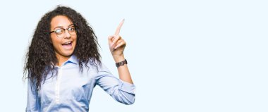 Kıvırcık saçlı giyen ile genç güzel iş kız başarılı fikirle işaret parmağı gözlük. Çıktıktan ve mutlu. Bir numara.