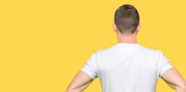 Yakışıklı adam geriye doğru uzakta silah ile vücut üzerinde seyir ayakta casual beyaz t-shirt giyen