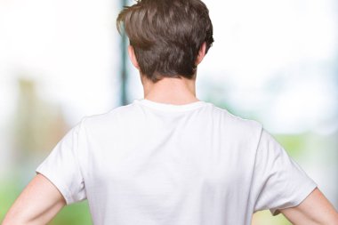 İzole arka plan ayakta geriye doğru uzakta silah ile vücut üzerinde seyir üzerinde rahat beyaz t-shirt giyen genç yakışıklı adam