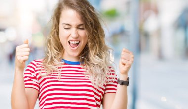 İzole arka kolları olan başarı için heyecanlı genç güzel sarışın kadın kutluyor zafer gülümseyen kaldırdı. Kazanan kavramı.