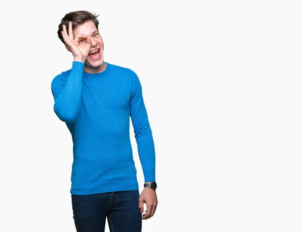 年轻英俊的男人穿着蓝色毛衣在孤立的背景做确定的手势与手微笑 眼睛通过手指看着快乐的脸 — 图库照片