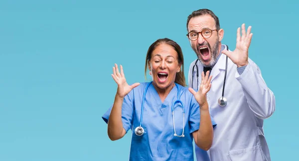 中年西班牙医生的伴侣夫妇穿着医疗制服在孤立的背景庆祝疯狂和疯狂的成功举起双臂和闭上双眼尖叫兴奋 优胜者概念 — 图库照片