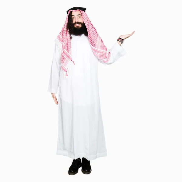 阿拉伯商人长头发 戴着传统的 Keffiyeh 微笑着愉快地呈现 用手掌指着镜头看着镜头 — 图库照片