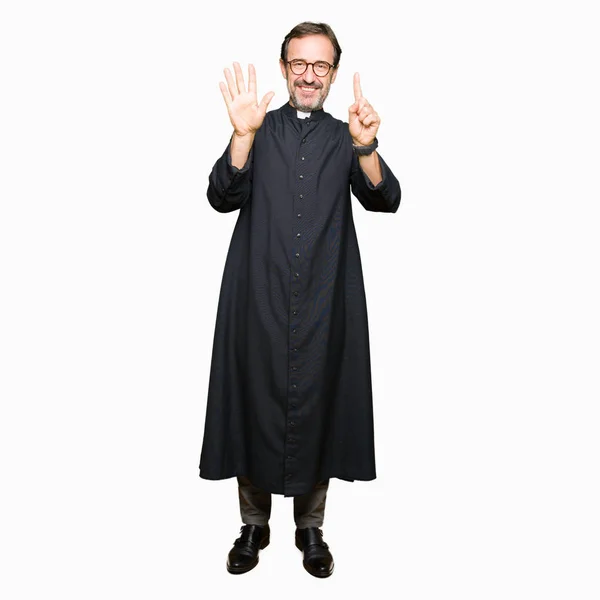 中年牧师男子穿着天主教长袍显示和手指第六 同时微笑着自信和快乐 — 图库照片