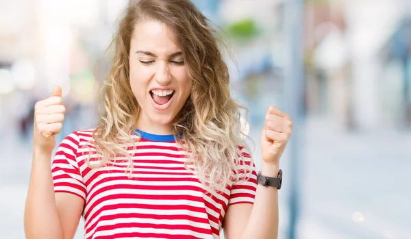 İzole arka kolları olan başarı için heyecanlı genç güzel sarışın kadın kutluyor zafer gülümseyen kaldırdı. Kazanan kavramı.
