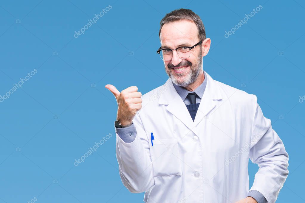 Middle age senior hoary professional man wearing white coat over isolated background smiling with happy face looking and pointing to the side with thumb up.