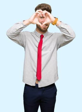 Genç yakışıklı iş adamı yapıyor kalp şekli ile el ve parmak işareti seyir gülümseyen