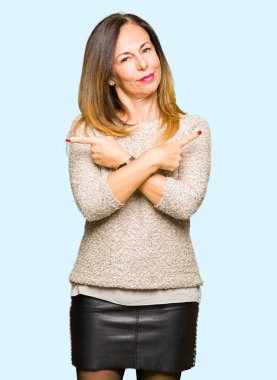 Moda kazak giyen güzel orta yaş kadın her iki parmak ile işaret eden, farklı yönde katılmıyorum