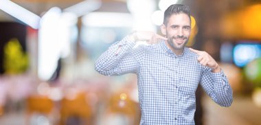 Tecrit edilmiş, güler yüzlü, kendine güvenen, parmaklarını, dişlerini ve ağzını gösteren genç yakışıklı bir adam. Sağlık kavramı.