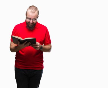 Gözlük takan ve ayakta ve diş gösterilen kendine güvenen bir gülümsemeyle gülümseyerek mutlu bir yüz ile izole arka plan üzerinde bir kitap okuma genç hipster adam
