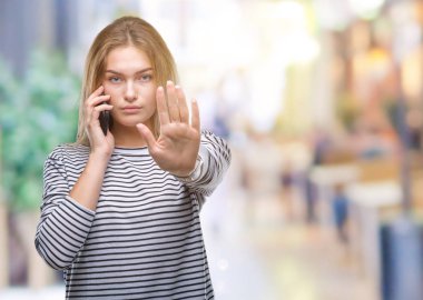 Genç kafkas kadın gösteren smartphone ekran açık eliyle dur işareti ile ciddi ve kendine güvenen ifade, savunma jest yapıyor izole arka plan üzerinde