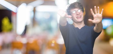 Gösterilen arka plan üzerinde gözlük takan genç yakışıklı adam izole ve parmakları ile işaret kendinden emin ve mutlu gülümseyerek süre 6 numara.