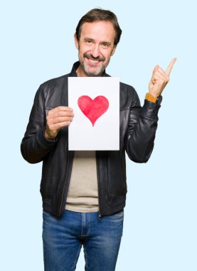 Kağıt kırmızı kalp ile çok mutlu el ve parmak ile tarafına işaret tutan yakışıklı orta yaş erkek