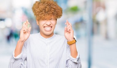 Genç yakışıklı iş adamı geçiş parmakları umut ve gözler gülümseyen şık gömlek giymiş afro saçlı kapalı. Şans ve batıl kavramı.