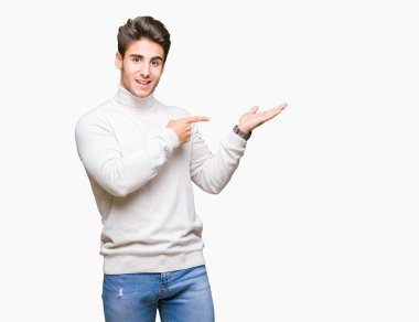 Üzerinden hayran ve el ile sunulması ve parmak ile işaret ederken kameraya gülümseyen izole arka plan balıkçı yaka kazak giyen genç yakışıklı adam.