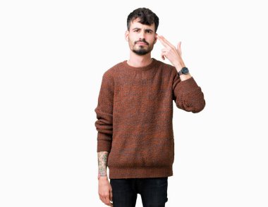 Genç yakışıklı adam giyen kış kazak izole üzerinde çekim ve öldürmek kendini el ve parmaklara baş, intihar jest işaret arka plan.