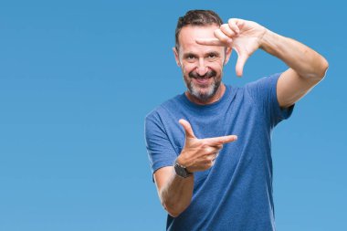 Orta yaş elle yapma çerçeve ve parmakları ile mutlu yüz gülümseyen izole arka plan üzerinde ağarmış komuta sizde. Yaratıcılık ve Fotoğrafçılık kavramı.
