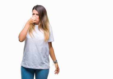 Genç güzel kadın rahat beyaz t-shirt üzerine izole bir şey pis ve iğrenç kokulu, dayanılmaz koku, holding nefes burun parmaklar ile arka plan. Kötü kokuyor kavramı.