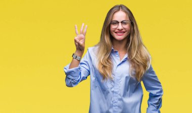 Genç güzel sarışın iş kadın gözlük gösterilen ve parmakları ile işaret izole arka plan üzerinde ise kendinden emin ve mutlu gülümseyerek üçüncüsü.