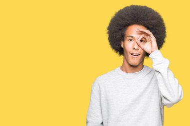 Sürpriz yüz, göz parmaklarının arasından seyir ile ok jest yapıyor sportif sweatshirt giyen afro saçlı genç Afro-Amerikan adam şok. İmansız ifade.