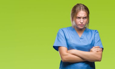 İzole arka plan şüpheci ve sinir, onaylamayan ifade yüz çapraz kolları olan cerrah üniforma giyen genç beyaz hemşire kadın. Negatif kişi.