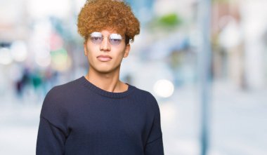 Afro yüzünde ciddi bir ifade ile gözlük takan genç yakışıklı adam. Basit ve doğal kameraya bakıyor.