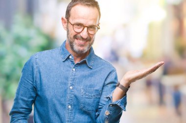 Orta yaş ağarmış komuta sizde neşeli sunulması ve kameraya bakarak avucunun ile işaret gülümseyen izole arka plan üzerinde gözlük.