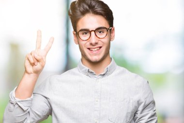 Gösterilen arka plan üzerinde gözlük takan genç yakışıklı adam izole ve parmakları ile işaret kendinden emin ve mutlu gülümseyerek ise ikinci.