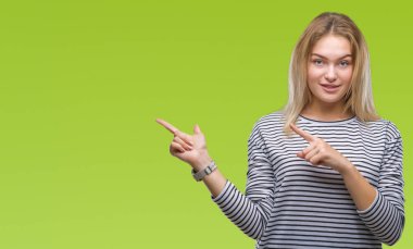 Gülümseyen ve iki elleri ve parmakları ile tarafına işaret kamera bakarak izole arka plan üzerinde beyaz kadın.