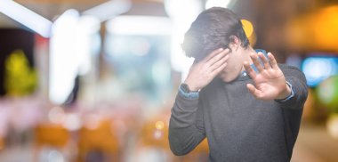 Genç yakışıklı zarif adam izole elleriyle gözlerini kapsayan arka plan ve stop jest ile acı ve korku ifadesi. Utandım ve negatif kavramı.