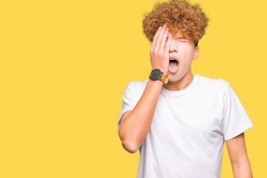 Casual beyaz t-shirt Yawning giyen afro saçlı yakışıklı delikanlı yarım yüz, göz ve ağız el ile kapsayan yorgun. Acı yüzü acıyor.