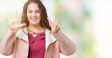 Parmakları ile sekiz kendinden emin ve mutlu gülümseyerek sırasında gösterilen ve yukarı dönük izole arka plan üzerinde kış ceket giyen boyutu genç kadın artı güzel numara.