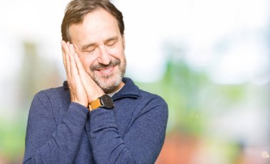 Uyku yorgun hayal ve eller ile birlikte Kapalı gözlerle gülümseyerek poz bir kazak giyen orta yaş yakışıklı adam.