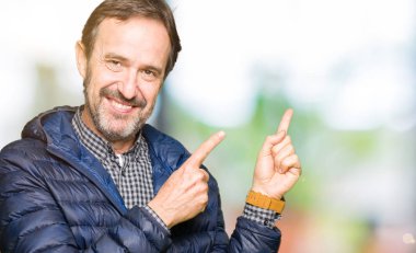 Orta yaş yakışıklı adam giyen kış ceket gülümseyen ve iki elleri ve parmakları ile tarafına işaret kamera bakıyor.