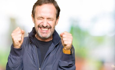 Orta yaş yakışıklı adam bir ceket silah ile başarı için heyecanlı zafer kutluyor gülümseyen kaldırdı. Kazanan kavramı.