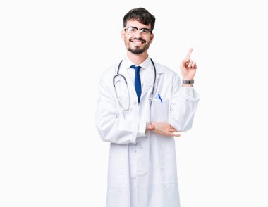 Yüzünde kocaman bir gülümseme ile izole arka plan üzerinde hastane ceket giyen adam kameraya bakarak yan el ve parmak ile işaret eden genç doktor.