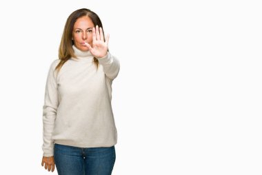 Güzel orta yaş yetişkin kadın giyiyor kış kazak stop yapıyor izole arka plan üzerinde şarkı elin avuç ile. Negatif ve ciddi bir jest yüz ifadesiyle uyarı.