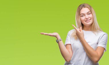 Hayret ve el ile sunulması ve parmak ile işaret ederken kameraya gülümseyen izole arka plan üzerinde beyaz kadın.