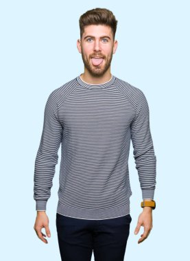 Genç yakışıklı adam dilini giyen çizgili süveter out komik ifade ile mutlu. Duygu kavramı.