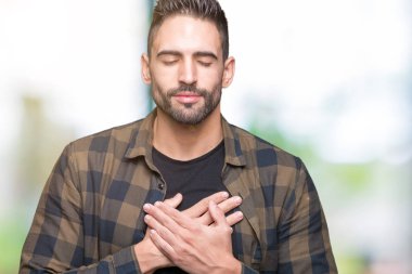 Yakışıklı delikanlı ile gülümseyen izole arka plan üzerinde kapalı gözler ve yüzünde minnettar jest ile göğüs üzerinde eller. Sağlık kavramı.