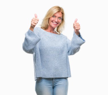 El ile pozitif jest yapıyor onaylama izole arka plan üzerinde kış kazak giyen orta yaş sarışın kadın başparmak gülümseyen ve başarı için mutlu. Kamera, kazanan jest arıyorsunuz.