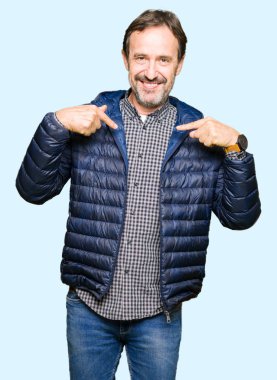 Yüzünde gülümseme ile kendinden emin görünüyorsun, kendini gururlu ve mutlu parmakları ile işaret kış ceket giyen orta yaş yakışıklı adam.