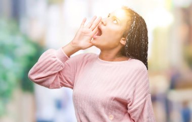 Genç örgülü saç Afro-Amerikan Kız bağırarak ve ağzı üzerinde el ile yan için çığlık izole arka plan üzerinde kazak giyiyor. İletişim kavramı.