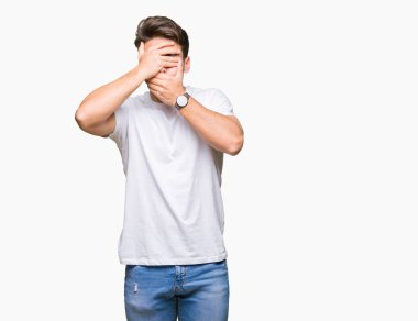 Yakışıklı delikanlı izole arka plan kaplaması gözler ve ağız el ile üzerine beyaz t-shirt giyen şaşırttı ve şok. Duygu gizleme